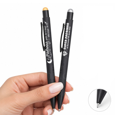 Duas canetas pretas personalizadas com textos e ícones espaciais em branco, com bolas dourada e prateada no topo, mostradas em mão feminina.