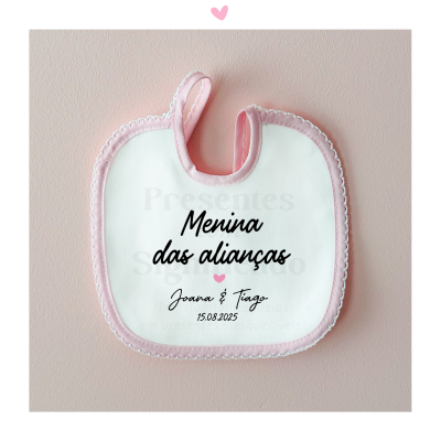 Babete branco com borda rosa e texto personalizado pendurado numa parede rosa