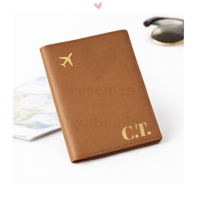 Carteira castanho claro em material semelhante a couro com símbolo dourado de avião e iniciais C.T.