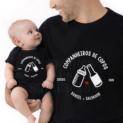 Pai e bebé com roupa preta com impressão branca e vermelha com texto e imagens de biberão e garrafa