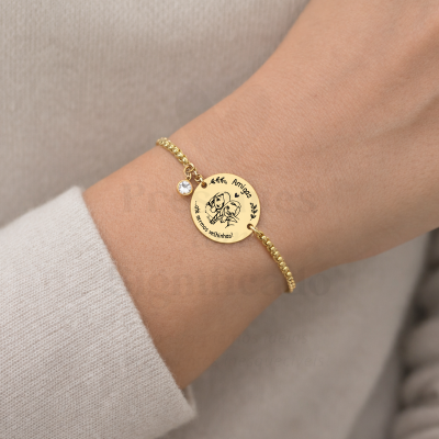 Pulseira dourada com pendente redondo gravado e pedra branca