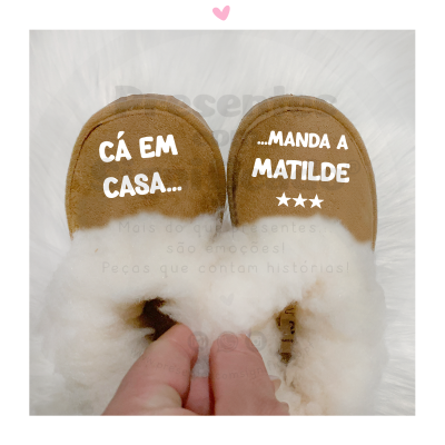 Chinelos marrons com interior felpudo branco e texto impresso em branco
