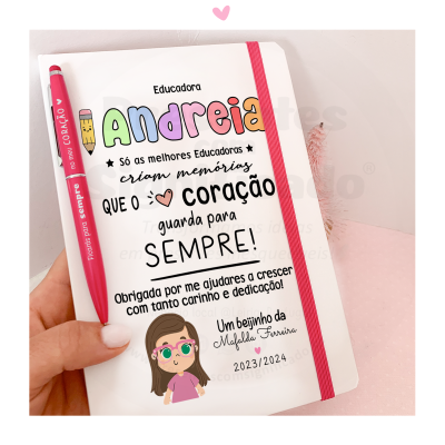 Caderno branco com elástico rosa e caneta vermelha, dedicatória para educadora Andreia com texto colorido e ilustração de menina.
