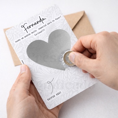 Cartão com coração para raspar e texto em português, mãos a raspar com moeda