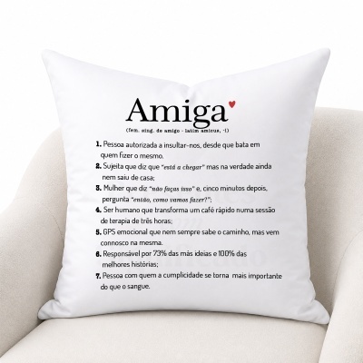 Almofada branca com texto Amiga e definição em português sobre uma cadeira creme.