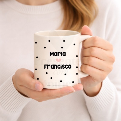 Caneca branca com bolinhas pretas e texto personalizado, segurada por mãos femininas.