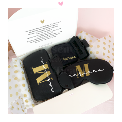 Conjunto de acessórios pretos personalizados com nome Mariana e iniciais douradas numa caixa branca com papel de bolinhas douradas.