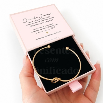 Pulseira dourada com nó em caixa rosa com texto a perguntar se aceita ser dama de honra