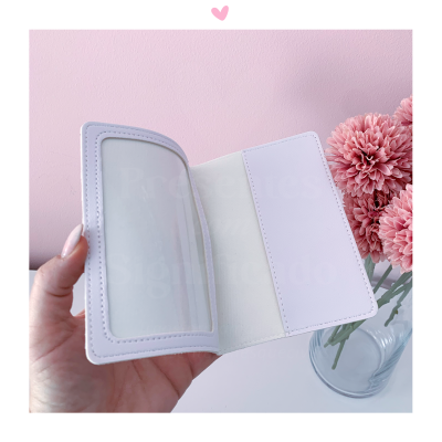 Carteira porta-cartões branca aberta em mão com flores cor-de-rosa ao fundo