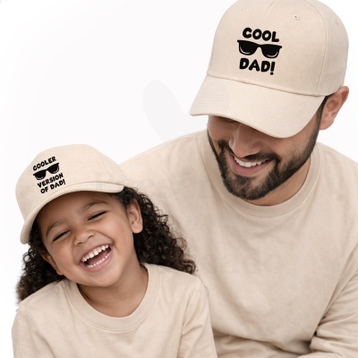 Adulto e criança com bonés e camisolas bege com mensagem relacionada com o pai