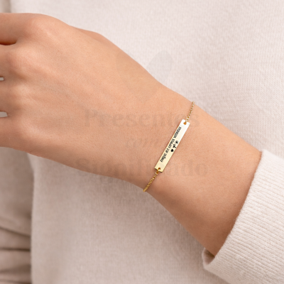 Pulseira dourada com placa retangular gravada no pulso