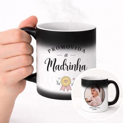 Caneca preta e branca com texto e ilustração segurada por mão.