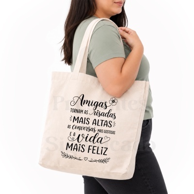 Mala de pano bege com texto em preto sobre amizade, usada por mulher com t-shirt verde.