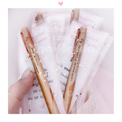 Canetas douradas embaladas individualmente com texto 'Lembrança do 1º Comunhão'