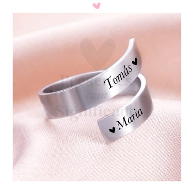 Anéis de prata gravados com 'Tomás' e 'María' sobre tecido rosa claro