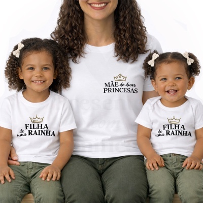 T-shirts brancas com frases em português e coroas douradas usadas por mãe e duas filhas sentadas.
