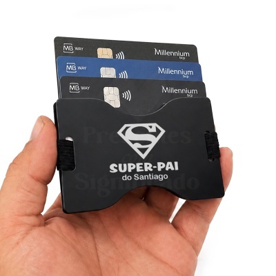 Carteira preta com símbolo de Super-Homem e texto SUPER-PAI do Santiago com três cartões Millennium bcp inseridos