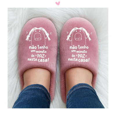 Chinelos cor-de-rosa com desenho e texto em branco, usados por pessoa com jeans.