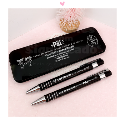 Estojo metálico preto com texto branco e duas canetas pretas sobre fundo rosa