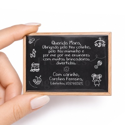 Placa de madeira pequena com texto em branco sobre fundo preto e moldura de madeira clara, com desenhos infantis brancos.