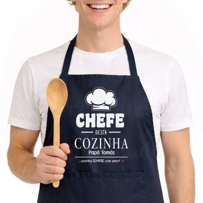 Pessoa a usar avental azul escuro com texto branco e colher de pau.