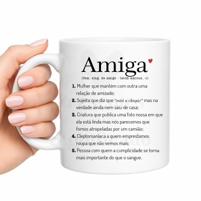 Caneca branca com definição de Amiga em português, segurada por mão feminina com unhas pintadas de rosa claro.