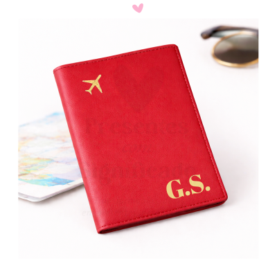 Capa vermelha para passaporte com avião e iniciais douradas