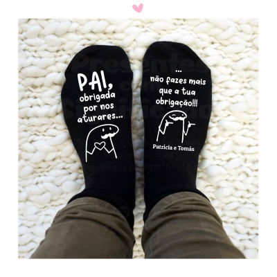 Meias pretas com texto branco em português sobre superfície têxtil branca