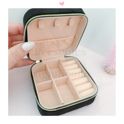 Estojo organizador de joias preto e rosa aberto, exibindo compartimentos para anéis e outras joias.