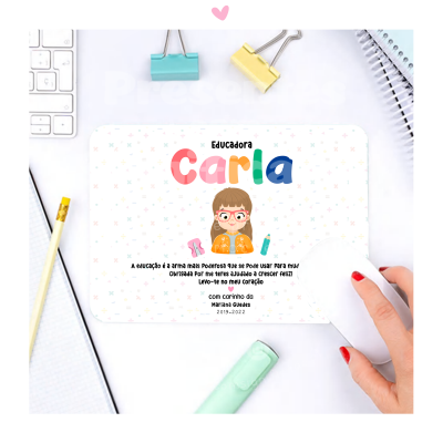 Cartão branco colorido com nome 'Carla' e ilustração de criança sobre mesa de escritório
