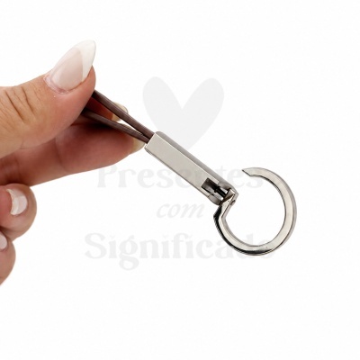Unhooker metálico prateado com cabo castanho segurado por mãos femininas