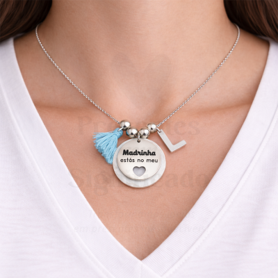 Colar prateado com pendente redondo e borla azul num pescoço com t-shirt branca