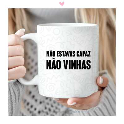 Caneca branca de cerâmica com texto em preto segurada por mulher com casaco cinza