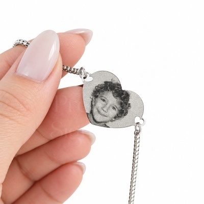 Pulseira prateada com pendente de coração gravado com a imagem de um menino