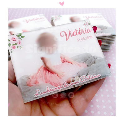 Embalagem com foto de criança vestida de rosa e texto de batismo em fundo com bolinhas