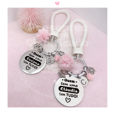 Conjunto de dois chaveiros personalizados com nomes e acessórios decorativos cor de rosa sobre fundo rosa.
