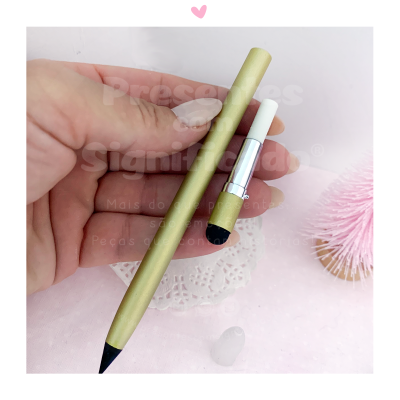 Lápis dourado com ponta preta e aparelho branco pequeno de ponta preta segurados por uma mão