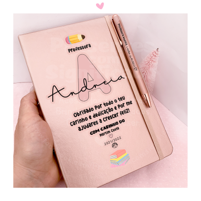 Caderno rosa personalizado com texto agradecendo uma professora e caneta correspondente