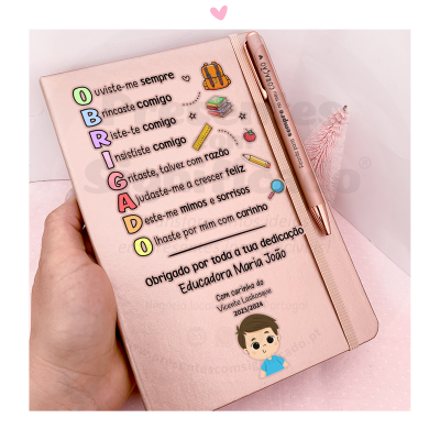 Caderno rosa com texto e caneta metálica rosa sobre superfície rosa