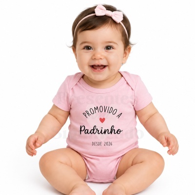 Bebé sorridente com body rosa e fita de cabelo rosa com laço.