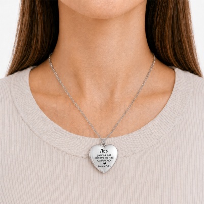 Colar prateado em forma de coração com texto gravado ao pescoço de mulher com camisola clara