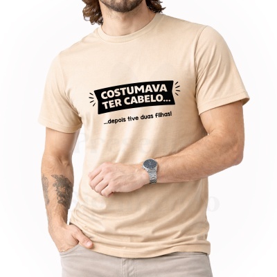 Homem a vestir t-shirt bege com texto preto e tatuagem num antebraço