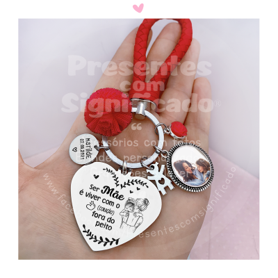 Porta-chaves com pulseira vermelha e três pendentes metálicos, incluindo um coração com texto em português.