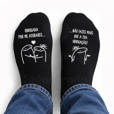 Meias pretas com desenhos e texto branco em pés com calças de ganga.