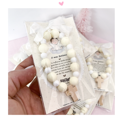 Pulseira de contas brancas e creme com cruz de madeira em embalagem plástica com cartão decorativo