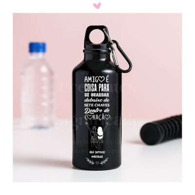Garrafa preta de metal com texto branco e mosquetão, sobre superfície branca e fundo rosa