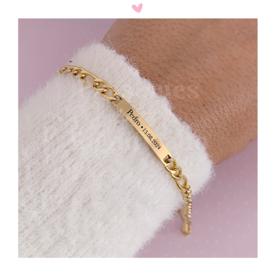Pulseira dourada com placa gravada usada num pulso com camisola branca felpuda