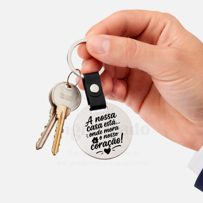 Chaveiro metálico redondo com frase em português segurado por mão masculina