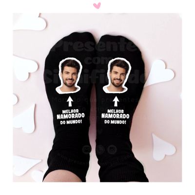Meias pretas com rosto masculino e texto MELHOR NAMORADO DO MUNDO em fundo claro com corações de papel
