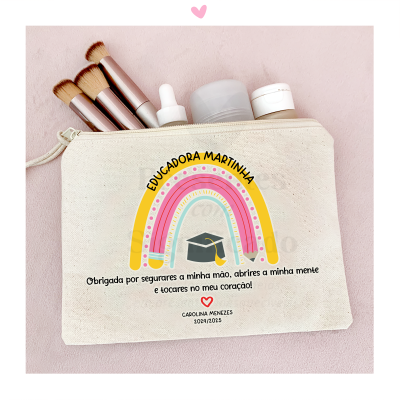 Necessaire bege com arco-íris colorido e texto personalizado, pincéis e frascos de maquilhagem sobre fundo rosa